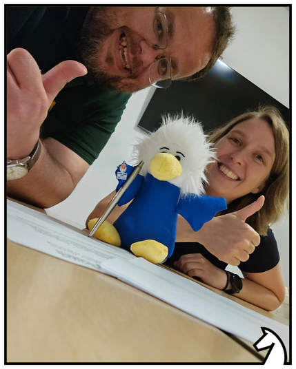 Maskottchen Chessy mit Stift in der Hand beim "Unterschreiben" des Arbeitsvertrags. Kristin und Geschäftsführer Niko zeigen den Daumen nach oben.