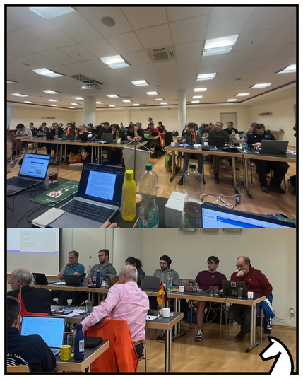 Blick in den Tagungsraum: Viele (v.a. junge) Menschen sitzen an Tischen. Vor ihnen stehen Tischfähnchen mit den Flaggen ihrer jeweiligen Landesverbände